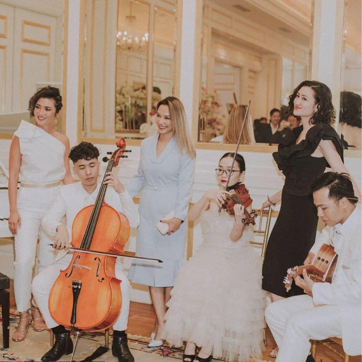 Dàn hòa tấu với cello, violin, guitar và vocalist biểu diễn trong không gian tiệc cưới.