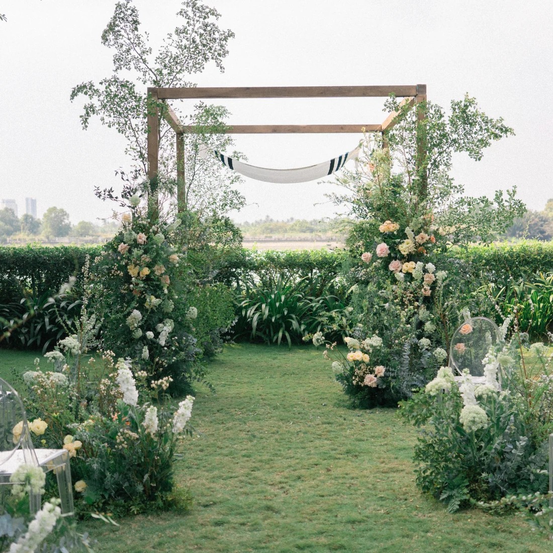 Cổng hoa của lễ cưới ngoài trời trên bãi cỏ bên sông.